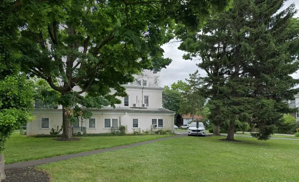 a white building with trees and grass