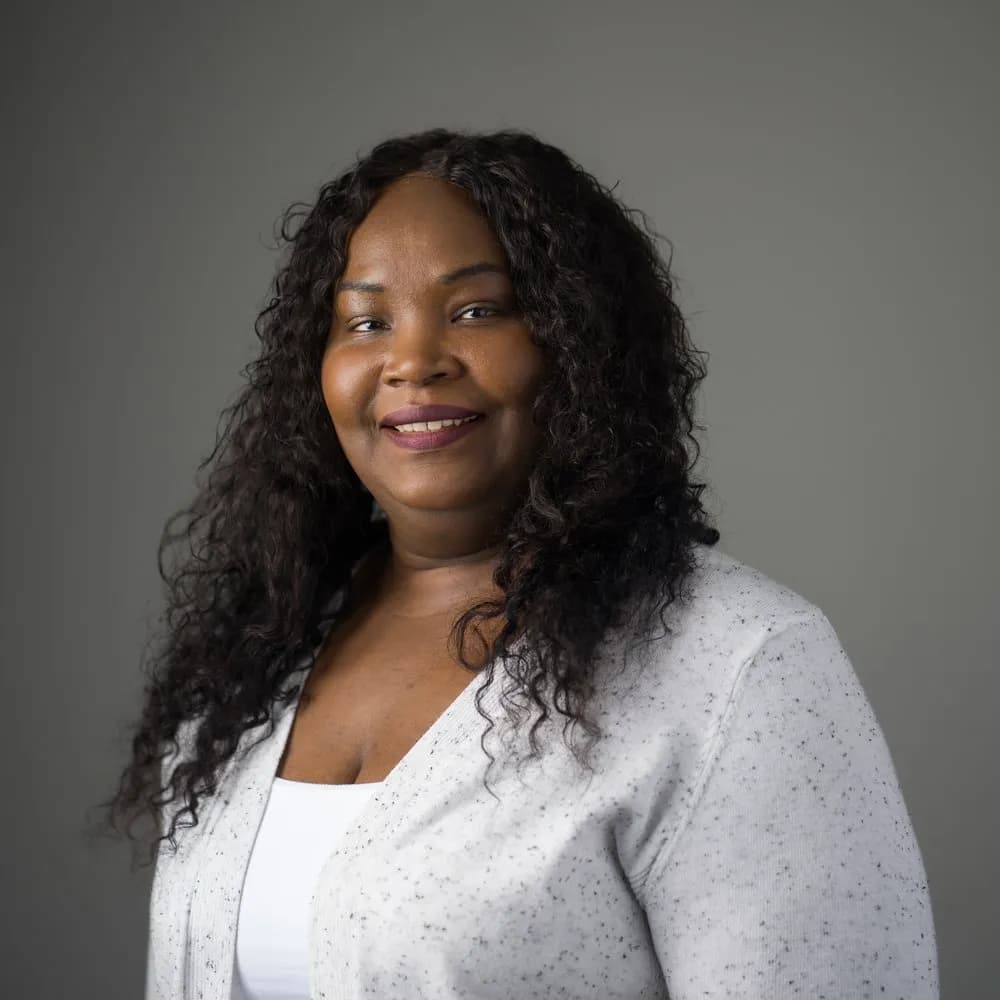 Dr. Racquel Assaye, Chief Financial Officer at Mental Health Partnerships, smiling and wearing a white blouse and gray cardigan.