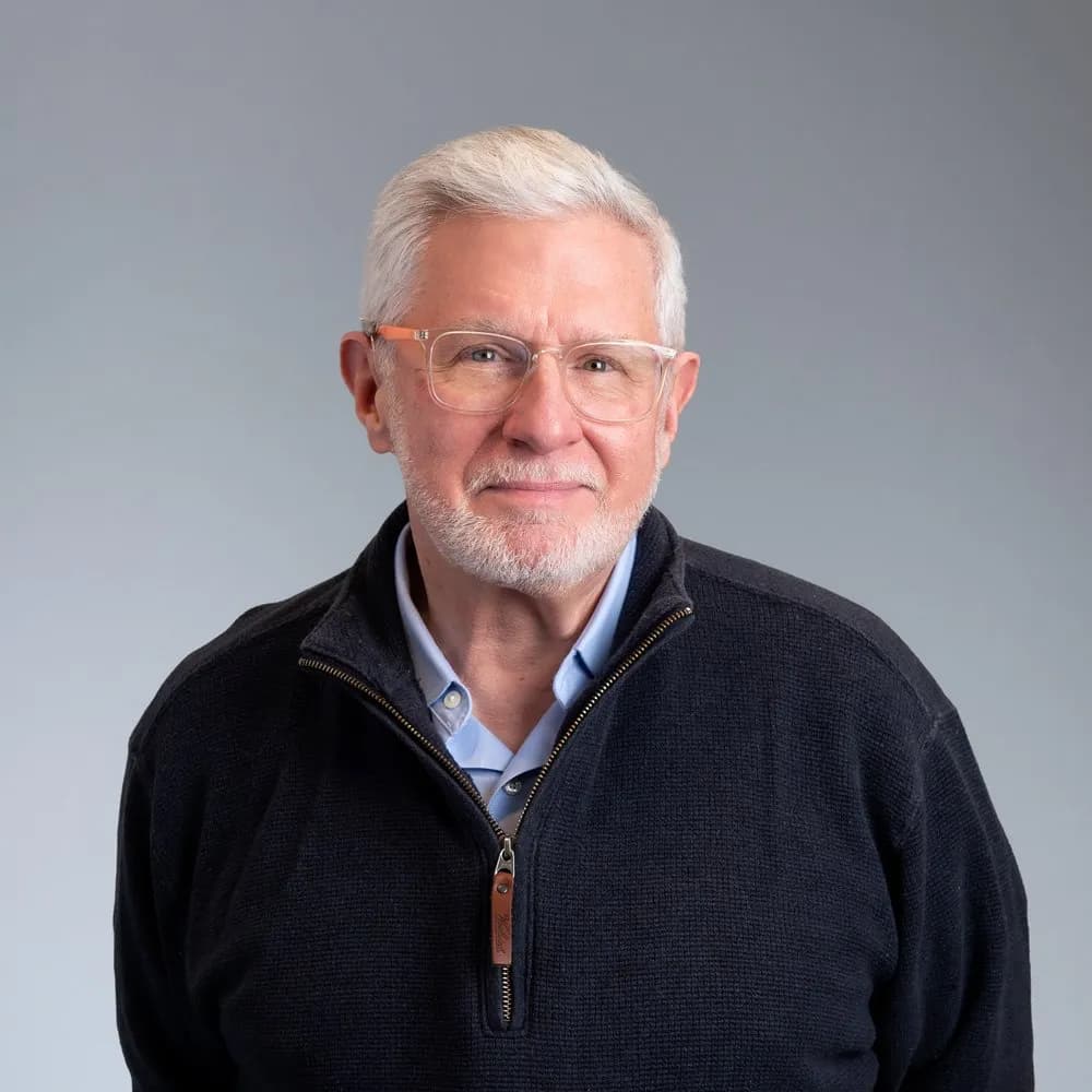 James Klasen, Learning and Development Specialist, wearing glasses and a black sweater, smiling gently at the camera.