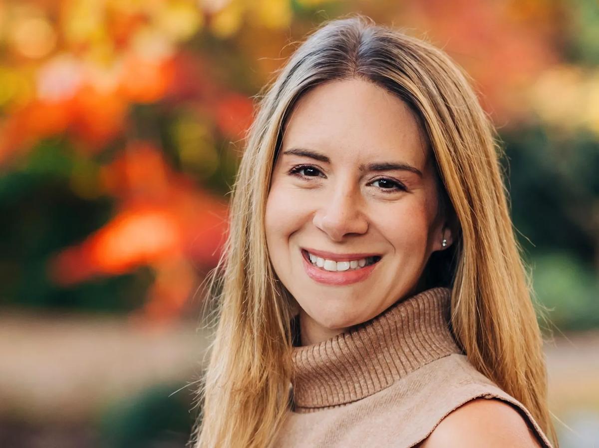 Irene M. Hurford, M.D., a white woman with light hair, smiling in front of a tall green hedge, wearing a light purple patterned blouse. She is the Board Chair at Mental Health Partnerships.