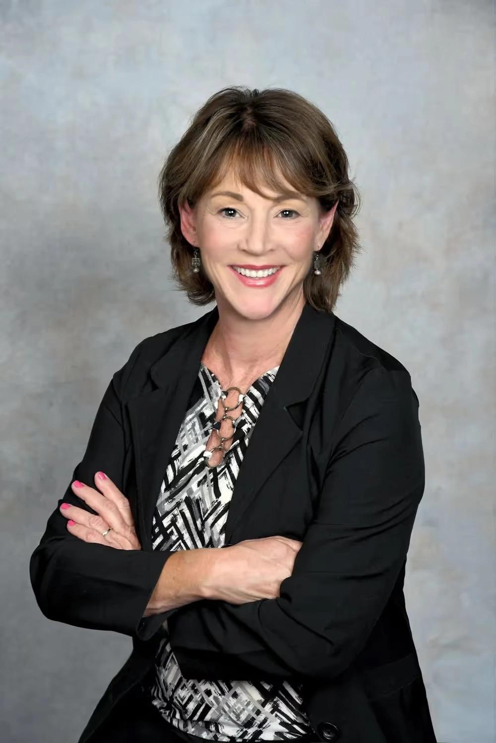Lisa Kubisiak, a white woman with blonde hair, smiling softly while wearing a mauve top and a patterned scarf. She is a Board Member at Mental Health Partnerships.