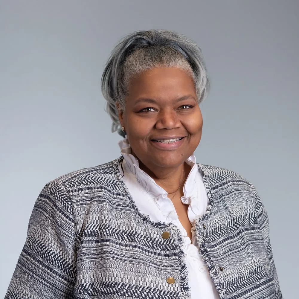 Lydia Cooper, Program Manager for Family Training, smiling and wearing a striped blazer and white blouse.