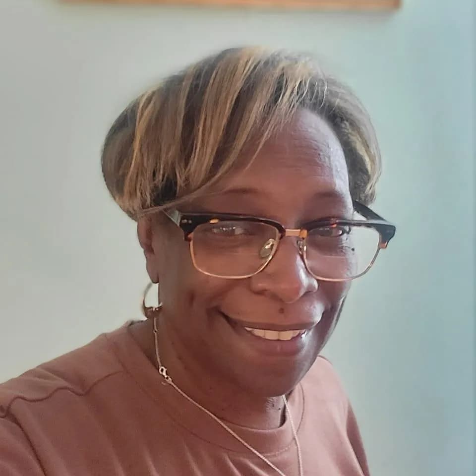 Mary Harper, Board Member at Mental Health Partnerships, smiling and wearing glasses and a light brown top.