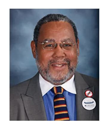 Roland Lamb, Board Member at Mental Health Partnerships, wearing a suit, blue shirt, and striped tie, smiling.