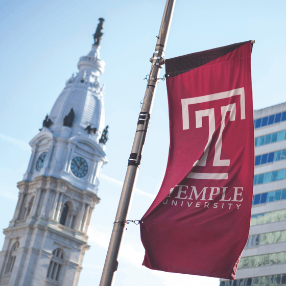 A photo of a temple university banner next to philadelphia city hall